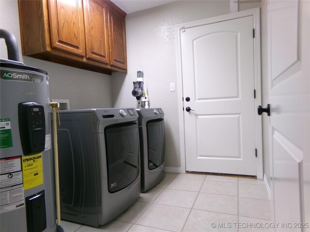 clothes washing area with washing machine and clothes dryer, cabinet space, electric water heater, and light tile patterned floors
