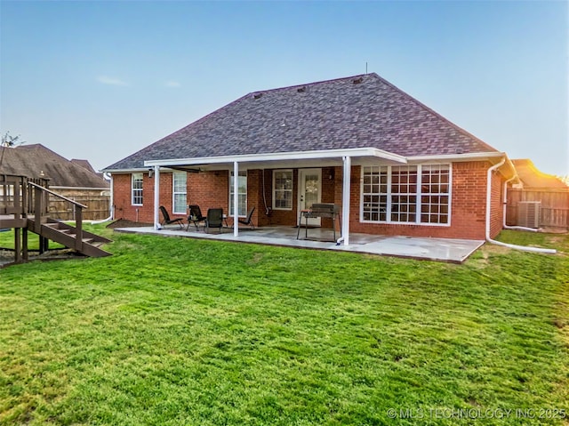 rear view of property with a patio, brick siding, fence, and a lawn