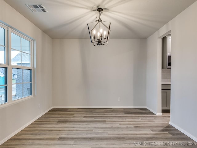 13406 E 124th St, Collinsville, OK 74021 - unfurnished room featuring light wood finished floors, baseboards, visible vents, and an inviting chandelier