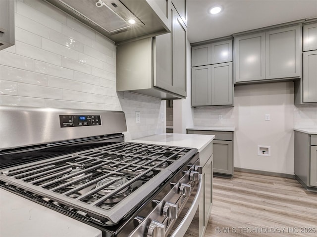 13406 E 124th St, Collinsville, OK 74021 - kitchen featuring light countertops, light wood-type flooring, stainless steel range with gas stovetop, gray cabinetry, and wall chimney range hood