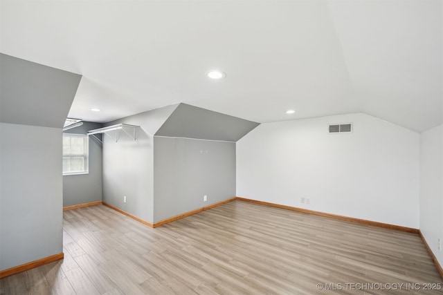 bonus room featuring baseboards, lofted ceiling, light wood-style flooring, and visible vents
