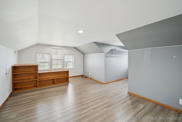 additional living space with baseboards, lofted ceiling, and wood finished floors