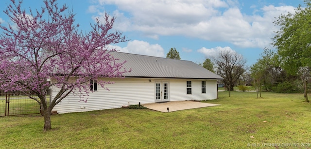 back of house with a patio area, french doors, fence, metal roof, and a lawn