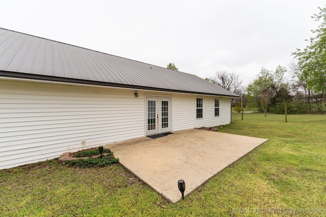 rear view of house featuring a lawn, metal roof, french doors, and a patio area