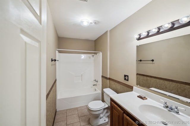 bathroom featuring toilet, vanity, shower / bath combination, tile patterned flooring, and wainscoting