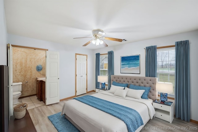 bedroom with multiple windows, light wood-style floors, ensuite bathroom, and a ceiling fan