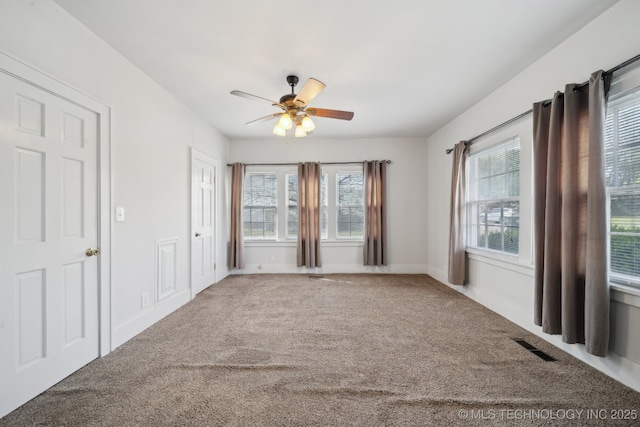 empty room featuring a ceiling fan, carpet floors, baseboards, and visible vents
