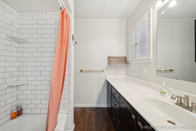 bathroom featuring crown molding, baseboards, wood finished floors, vanity, and shower / tub combo