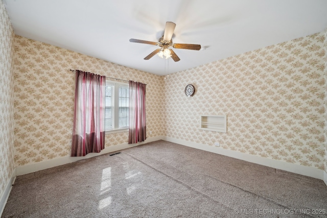 spare room featuring wallpapered walls, baseboards, ceiling fan, and visible vents