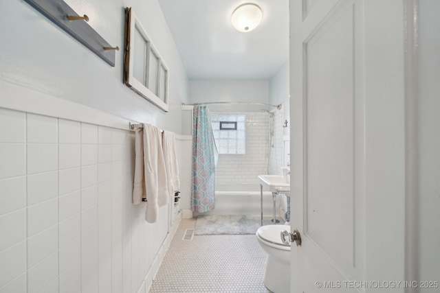 bathroom with toilet, shower / bath combo with shower curtain, tile walls, and visible vents