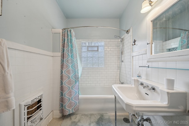 bathroom featuring heating unit, a sink, tile walls, and shower / bath combo with shower curtain