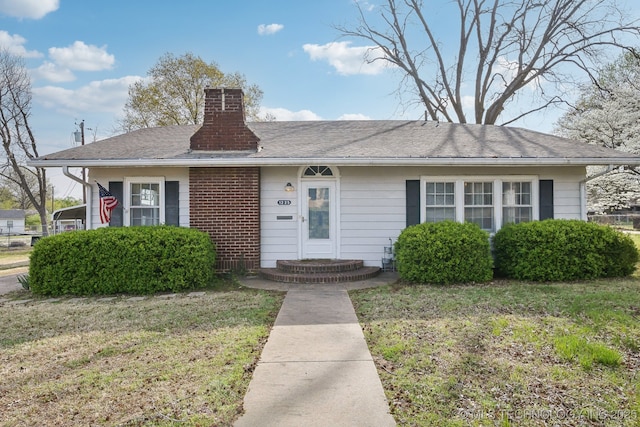 view of front facade featuring brick siding, a front lawn, and a chimney
