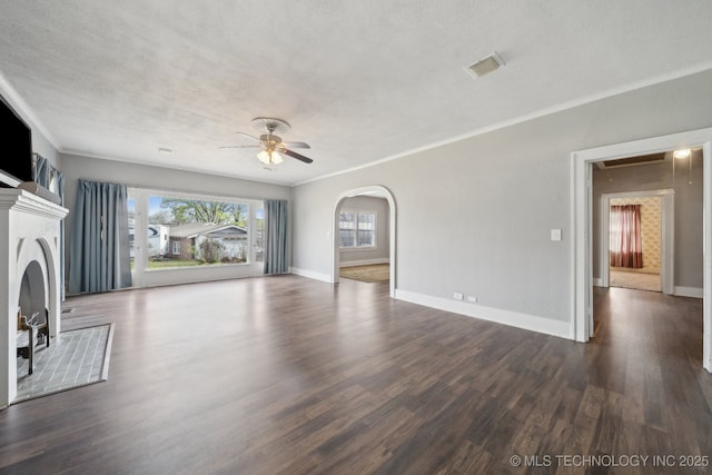 unfurnished living room featuring crown molding, baseboards, ceiling fan, and dark wood finished floors
