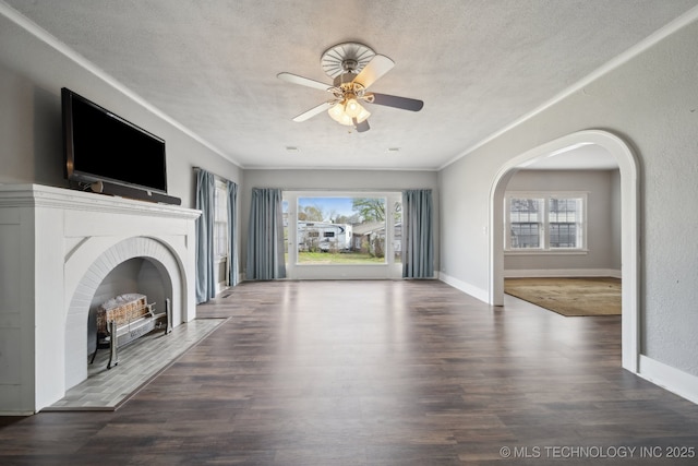 unfurnished living room featuring a wealth of natural light, wood finished floors, ceiling fan, and a textured ceiling