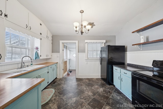 kitchen with a wainscoted wall, blue cabinetry, open shelves, black appliances, and an inviting chandelier