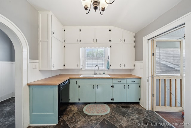 kitchen featuring a wainscoted wall, a chandelier, wooden counters, lofted ceiling, and a sink