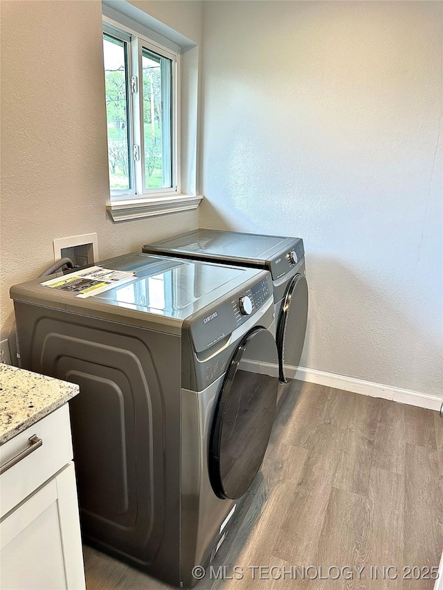 laundry room with independent washer and dryer, a textured wall, baseboards, cabinet space, and wood finished floors