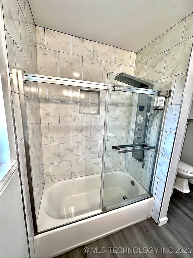 full bath featuring toilet, combined bath / shower with glass door, and wood finished floors
