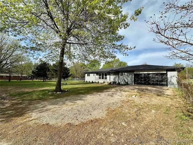 view of front facade featuring a front yard, driveway, an attached garage, and fence