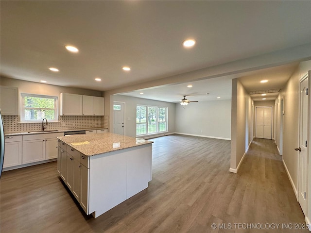 kitchen featuring backsplash, a wealth of natural light, a kitchen island, and a sink