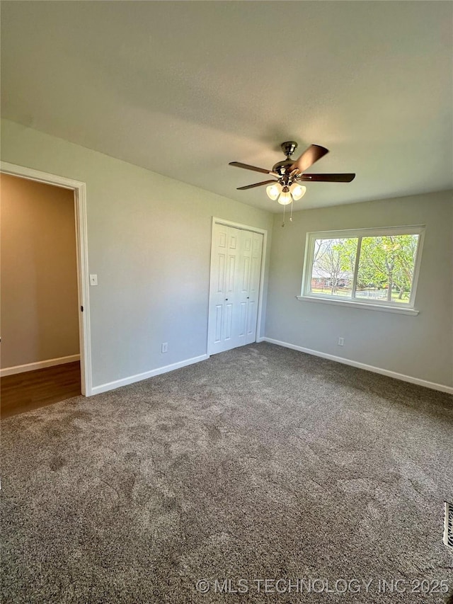 unfurnished bedroom with ceiling fan, a closet, carpet flooring, and baseboards