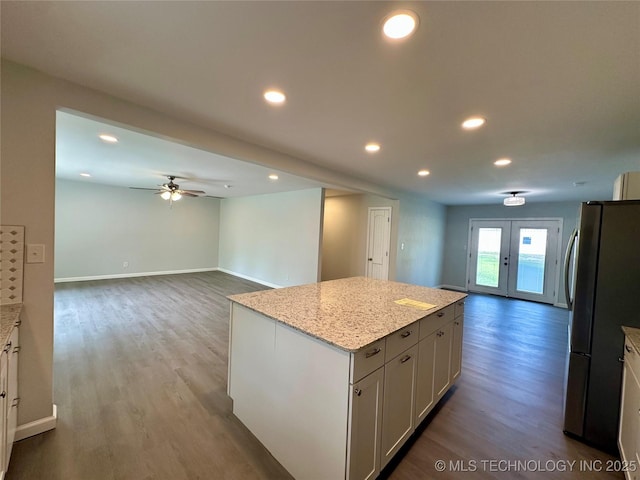 kitchen featuring recessed lighting, wood finished floors, a center island, freestanding refrigerator, and open floor plan