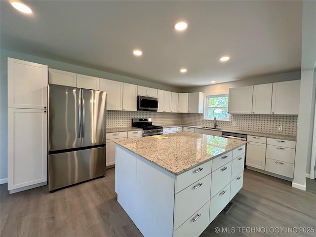 kitchen featuring appliances with stainless steel finishes, a kitchen island, dark wood-style floors, and a sink