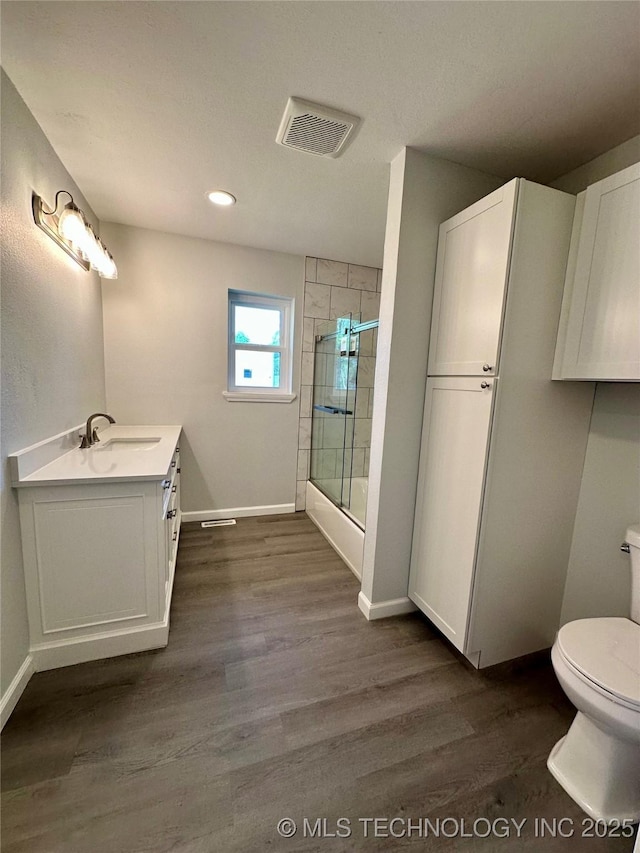 full bath with wood finished floors, toilet, vanity, baseboards, and visible vents