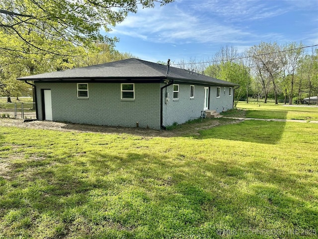 view of side of home with a lawn, entry steps, and brick siding