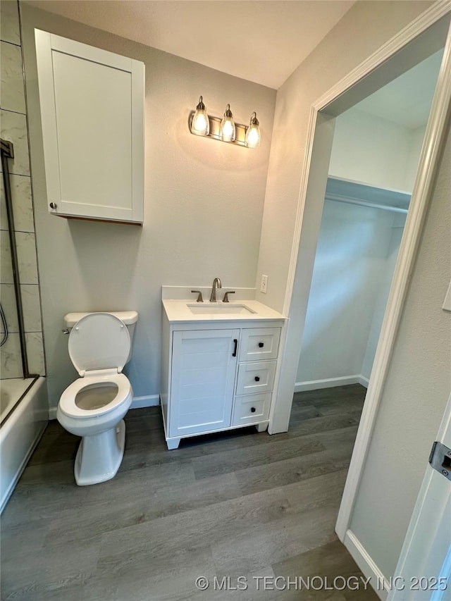 bathroom featuring toilet, vanity, wood finished floors, and baseboards