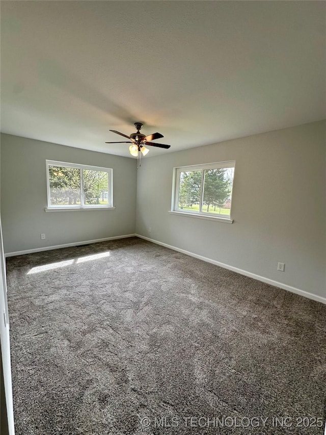 carpeted spare room with ceiling fan, plenty of natural light, and baseboards