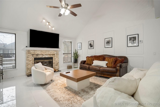 living room with a fireplace, a ceiling fan, high vaulted ceiling, and light tile patterned floors