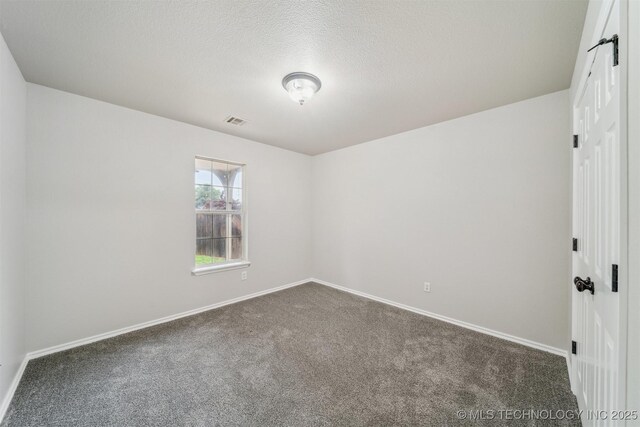 spare room with a textured ceiling, baseboards, visible vents, and carpet