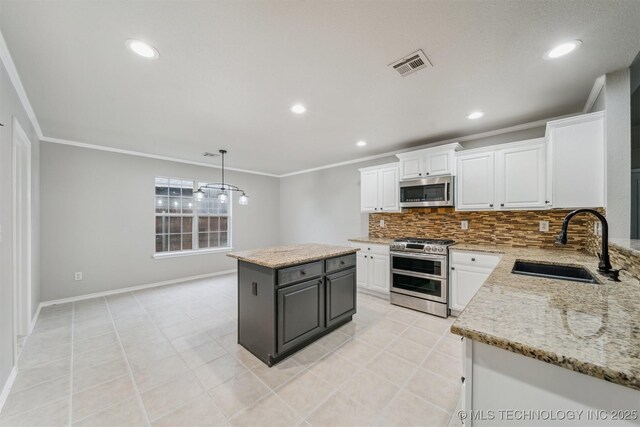 kitchen with visible vents, crown molding, a sink, white cabinets, and stainless steel appliances