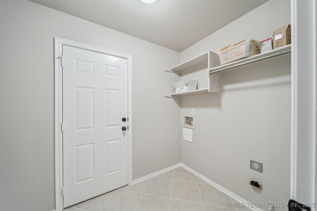 clothes washing area with light tile patterned floors, baseboards, laundry area, and hookup for a washing machine