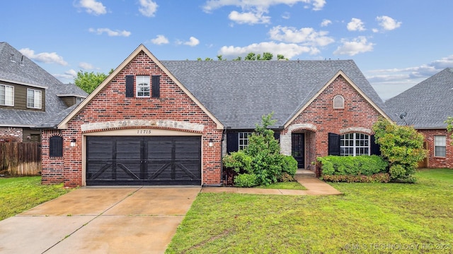 view of front of house with brick siding, driveway, a front yard, and roof with shingles