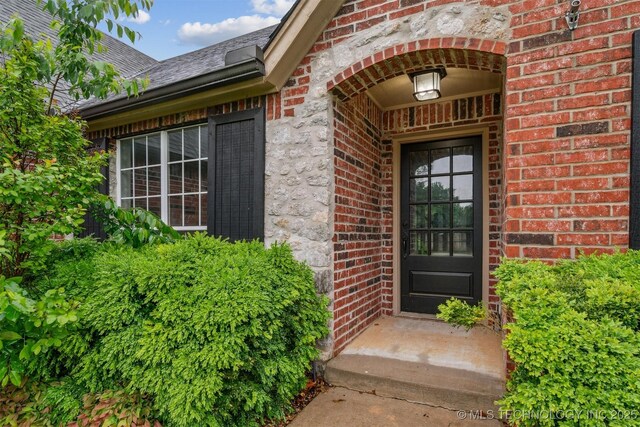 entrance to property with brick siding and roof with shingles