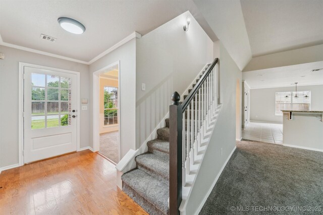 entryway with crown molding, baseboards, and visible vents