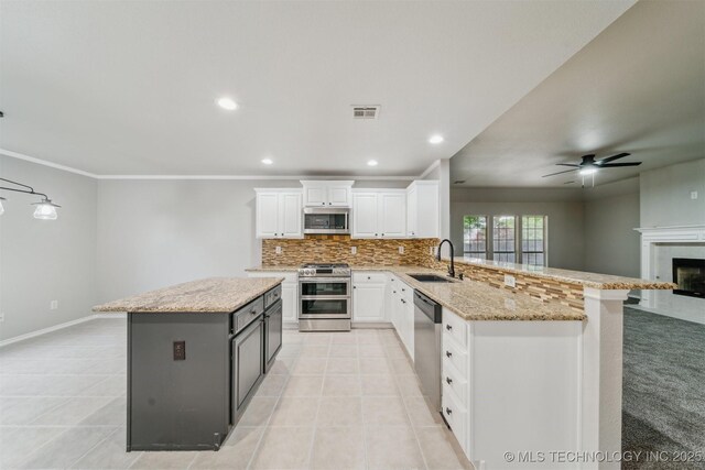 kitchen with appliances with stainless steel finishes, a sink, white cabinetry, a ceiling fan, and backsplash