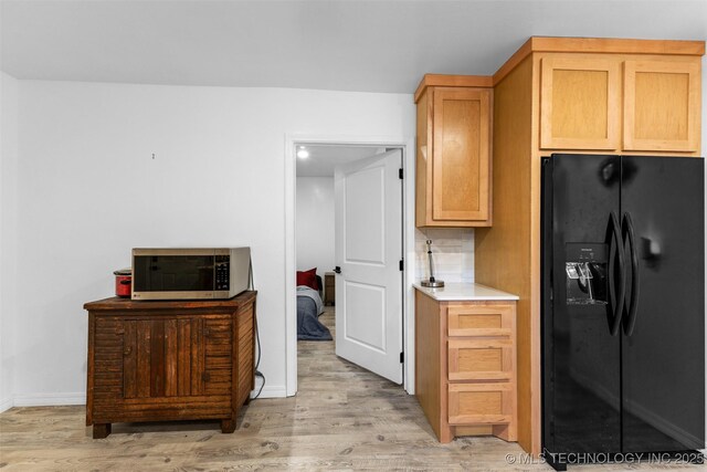 900 S Johnston, Ada, OK 74820 - kitchen featuring black fridge, stainless steel microwave, light wood-style floors, and baseboards