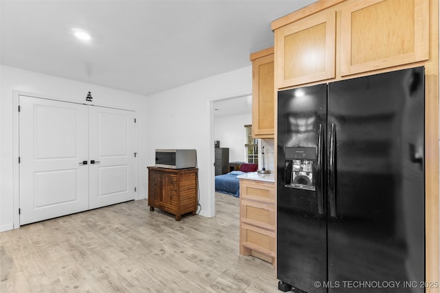 900 S Johnston, Ada, OK 74820 - kitchen with black fridge, stainless steel microwave, light brown cabinetry, light wood-style flooring, and light countertops