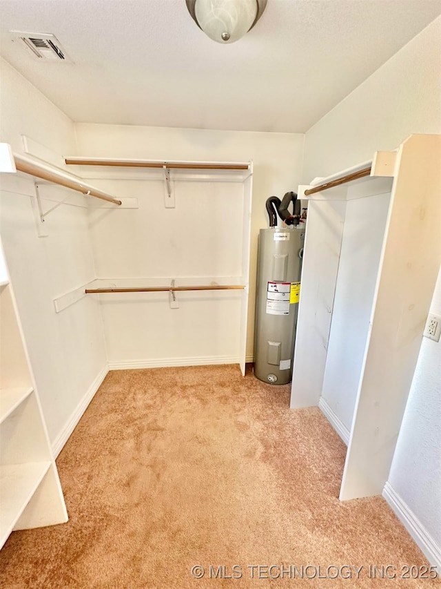 spacious closet with visible vents, electric water heater, and carpet floors