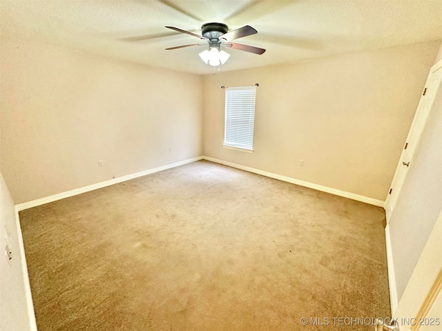 carpeted spare room featuring baseboards and a ceiling fan