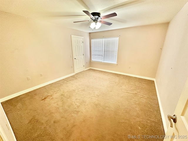 empty room with carpet flooring, baseboards, and a ceiling fan