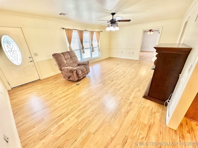 foyer entrance featuring ceiling fan, light wood-style flooring, ornamental molding, visible vents, and baseboards