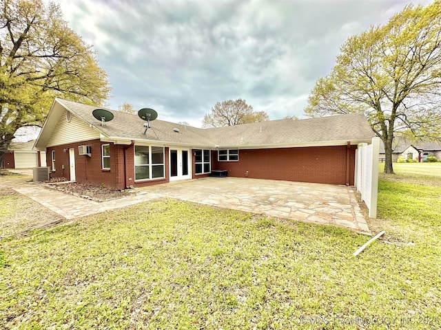 rear view of property with a wall unit AC, a lawn, a patio, brick siding, and french doors