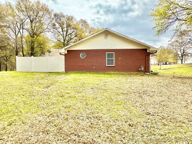 exterior space with brick siding, fence, and a lawn