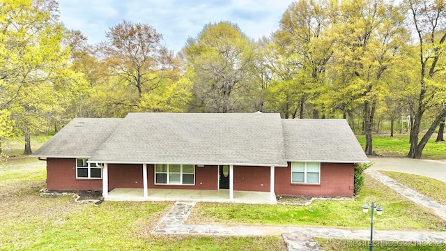 view of front facade with brick siding, a front lawn, and covered porch