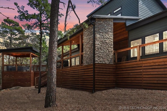 1739 NW 136th Rd, Wilburton, OK 74578 - property exterior at dusk with stone siding and a sunroom