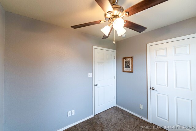 464888 E 1010th Rd, Sallisaw, OK 74955 - unfurnished bedroom with baseboards, dark carpet, and a ceiling fan